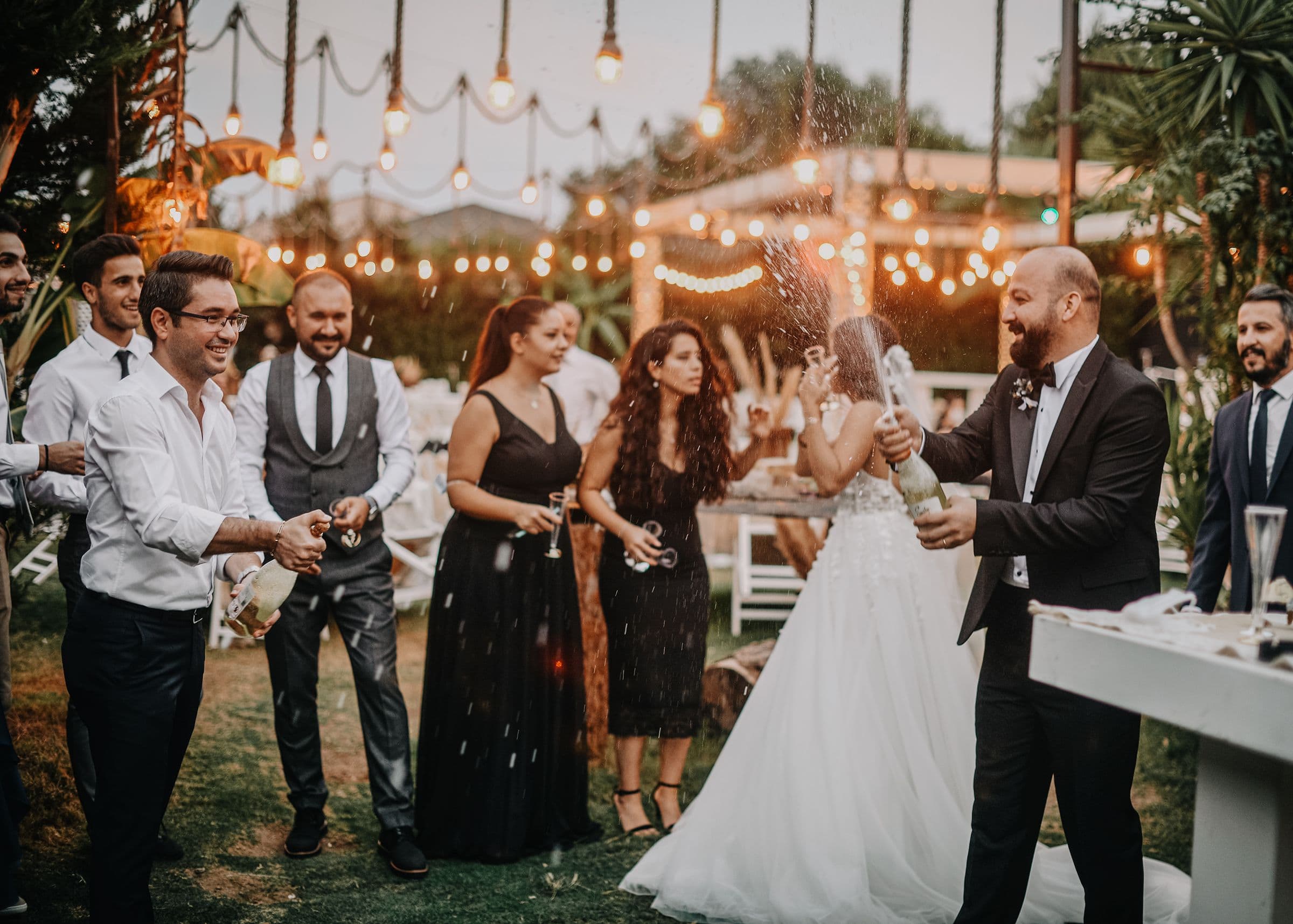 Guests in black tie spraying champagne at an evening reception