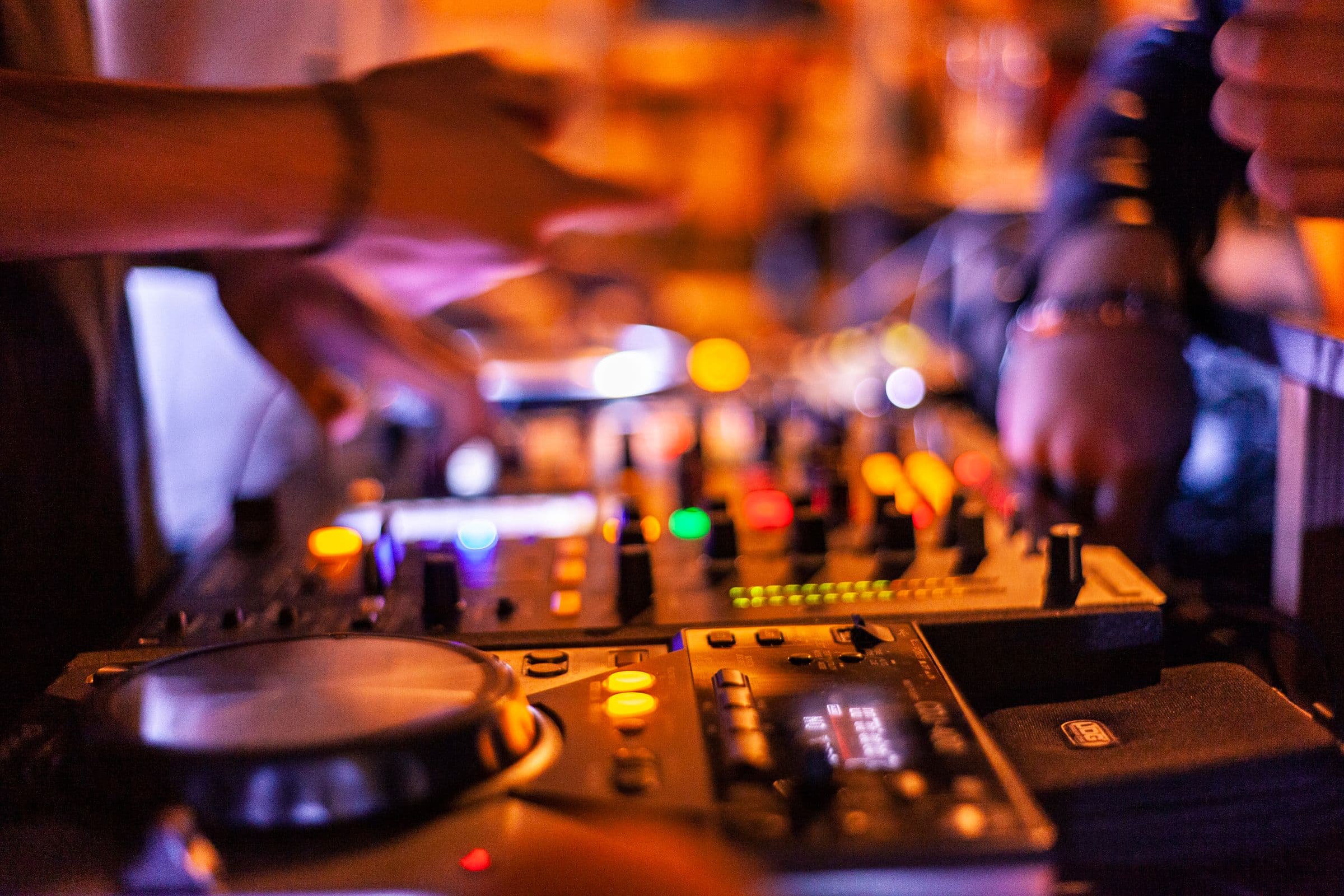 Close crop of hands working a DJ controller under warm light